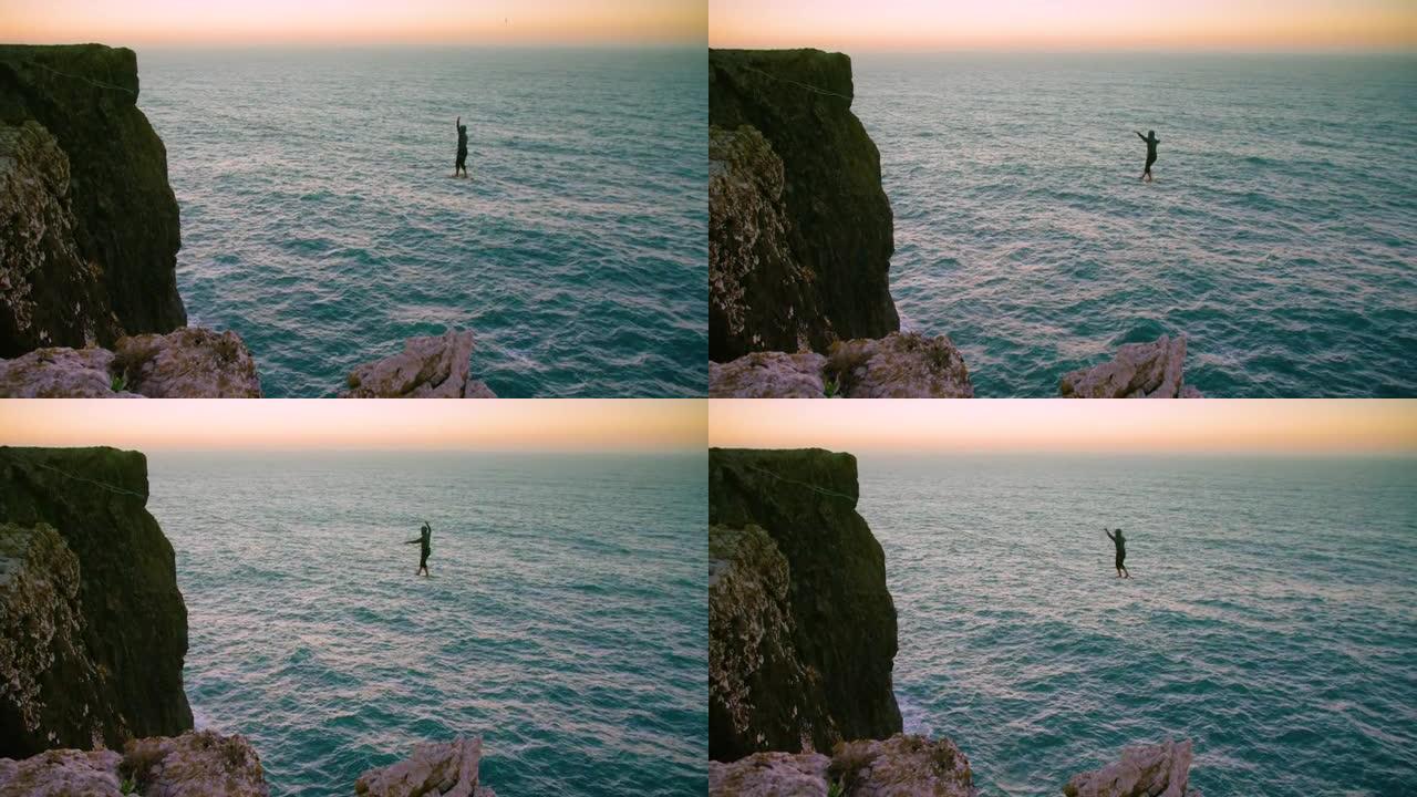 一位年轻的懒人慢慢地穿过两条悬崖之间的一条线。黄昏时在海洋上拍摄