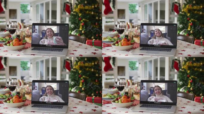 快乐的高加索女人，笔记本电脑上的咖啡躺在圣诞桌上