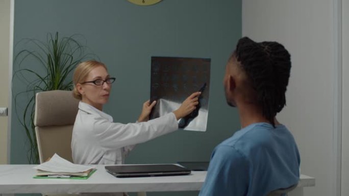 成熟的女医生在室内向男性患者解释MRI图像