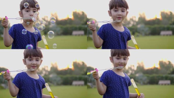 一个可爱可爱的小女孩孩子的特写美丽快乐镜头正在吹肥皂水泡泡