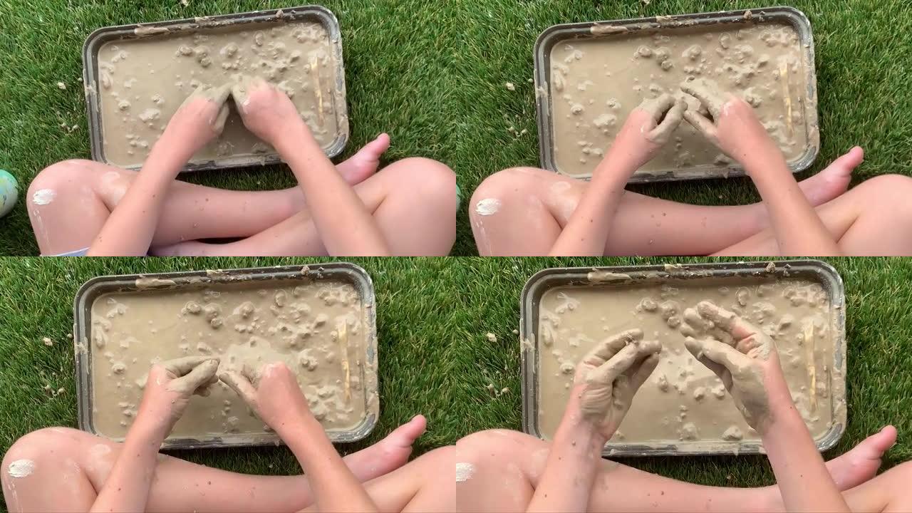 一个孩子的特写镜头，湿的，泥泞的手和肮脏的飞溅的腿和手臂，在玩湿的模型粘土时弄得一团糟。慢动作。