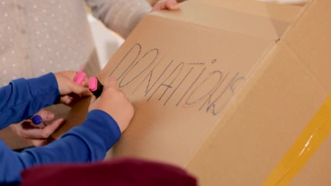男孩在cradborad盒子上用记号笔书写 “捐赠”