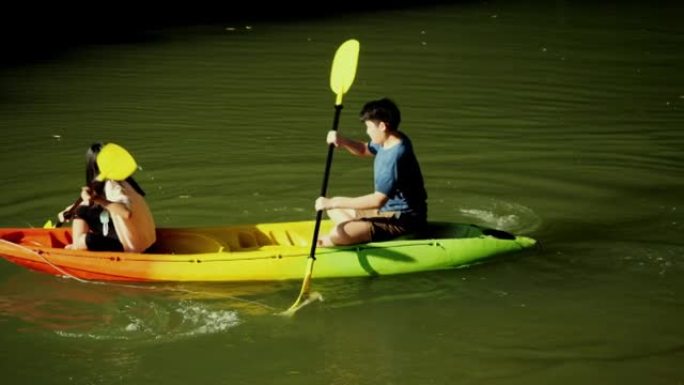 快乐的亚洲儿童在阳光明媚的日子里一起在河里划独木舟，生活方式理念。