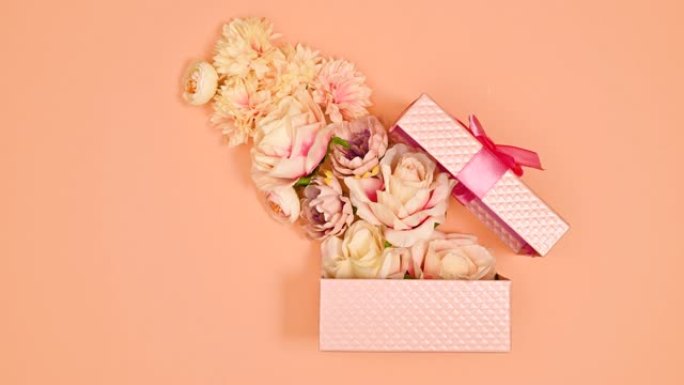 带丝带的粉彩粉色礼物出现在粉彩橙色主题上，鲜花从礼物中出来。停止运动