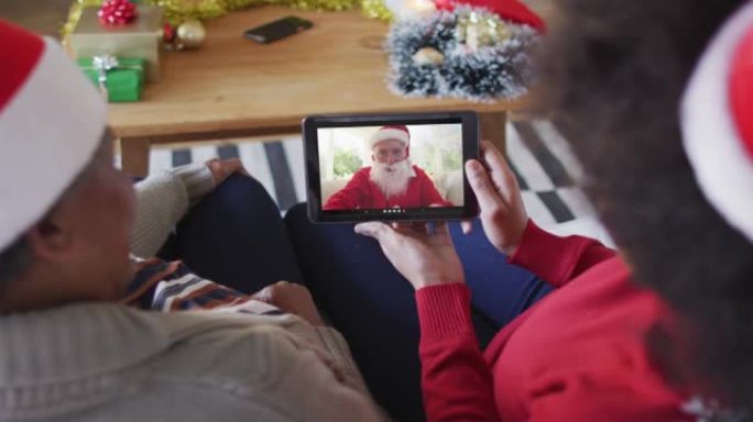 非裔美国母亲和女儿使用平板电脑与屏幕上的圣诞老人进行圣诞节视频通话
