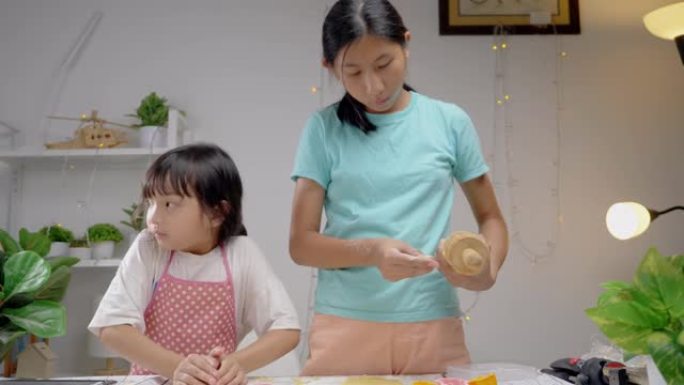 快乐的亚洲儿童在家学习制作饼干，女孩一起打谷糕点面团，生活方式理念。