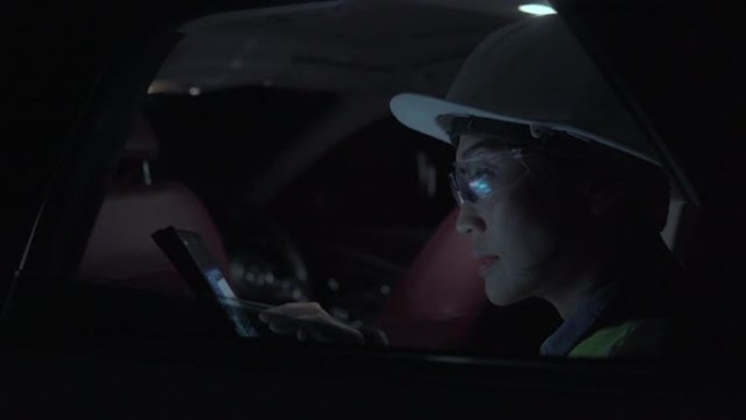 穿着制服的女主管在能源行业工作，晚上用汽车检查石化厂。