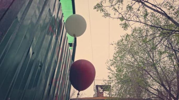 抑郁症，派对结束了。红色和白色气球设置在贫民窟的垃圾箱附近