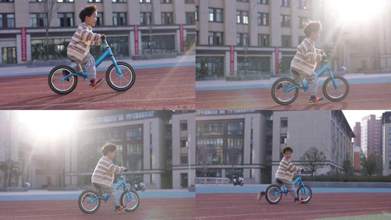 小男孩正在学校操场上骑自行车