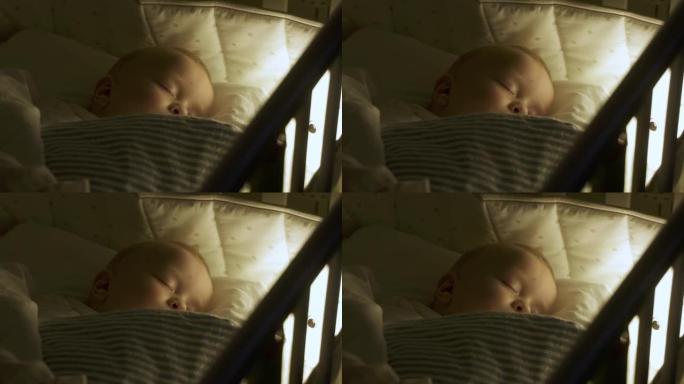 婴儿襁褓躺在婴儿床里，9个月的男婴睡在夜灯下。9个月大的高加索儿童特写镜头。