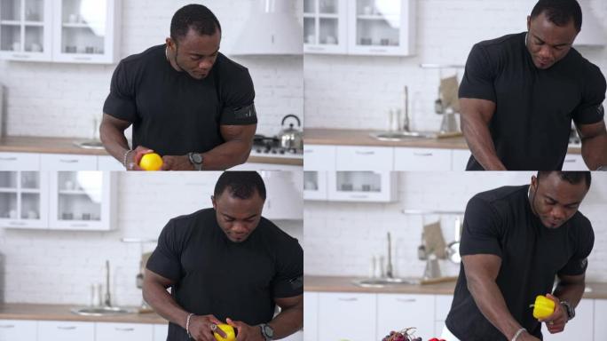 厨房里健康的非洲男人。穿着黑色t恤的英俊黑人男子，肌肉发达，用新鲜蔬菜烹饪食物。