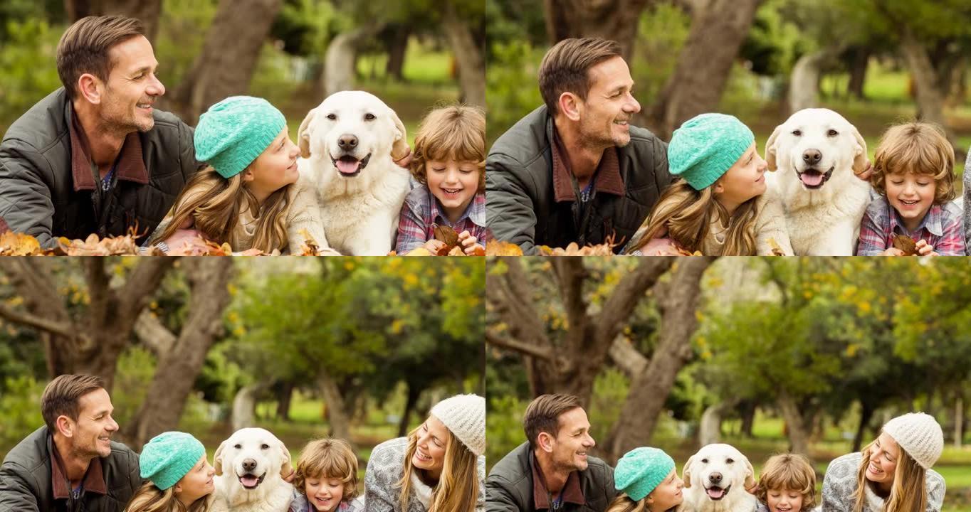 快乐的高加索父母，儿子和女儿与宠物狗躺在公园里