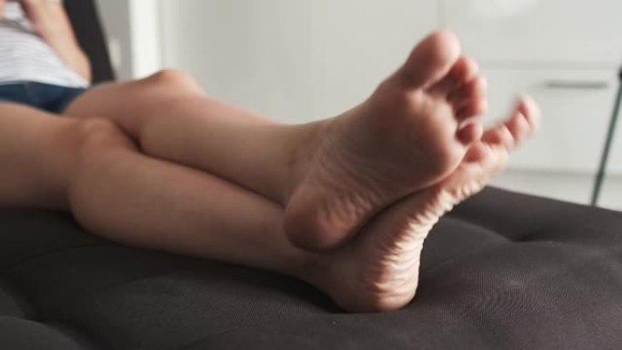 穿着便服的女人躺在沙发上休息时动脚