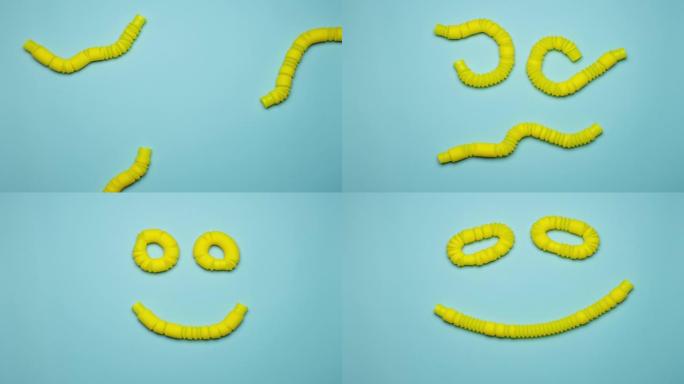 波纹黄色流行管玩具在背景上以幸福的笑脸的形式平滑爬行和连接。