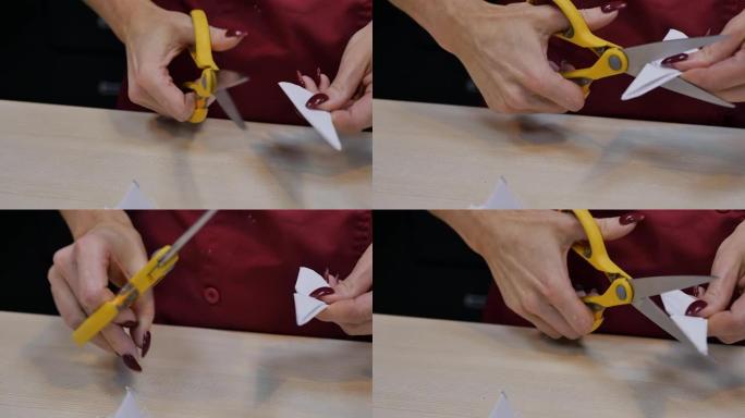 女人的手用红色指甲用黄色剪刀剪纸折纸