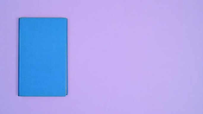蓝色精装书在紫色主题的不同侧面移动并打开。停止运动平铺