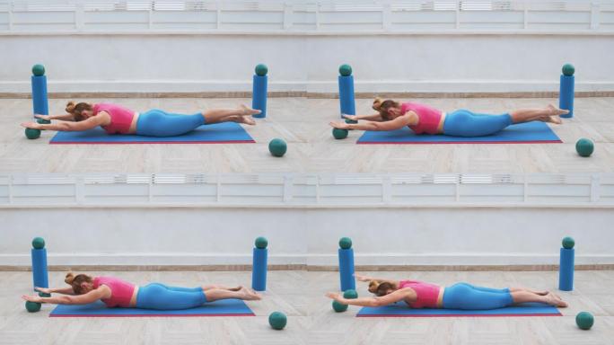 健身女子做伸展和背部伸展，在垫子上空气中移动腿