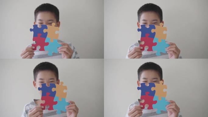 青少年男孩拿着拼图形状，青春期前儿童精神卫生概念，世界自闭症意识日，自闭症谱系障碍意识概念