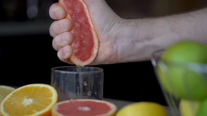 男性的手正在挤压成熟的葡萄柚，以制作柑橘汁，健康的生活方式，果汁