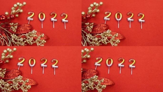 数字2022红色背景上的蜡烛。近红色圣诞花