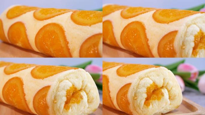 运动视频特写橙色蛋糕卷，木盘上有切成薄片的橙色水果。