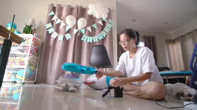 亚洲妇女在家里用电动气泵给气球充气