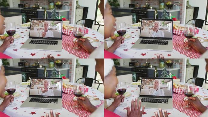非裔美国人夫妇与葡萄酒使用笔记本电脑进行圣诞节视频通话，屏幕上有幸福女人