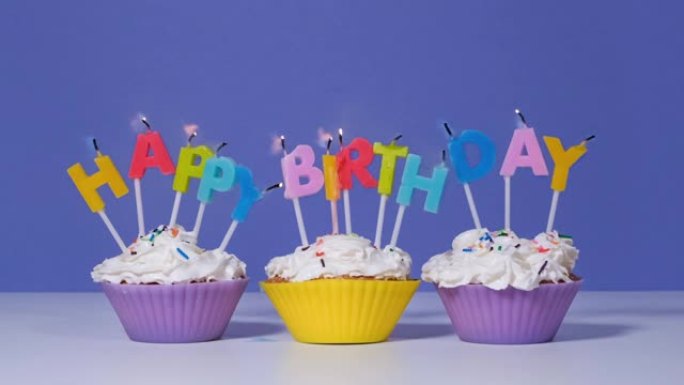 生日快乐铭文由在紫色背景上孤立的美味纸杯蛋糕上燃烧五颜六色的蜡烛制成。生日快乐视频横幅，慢动作全高清