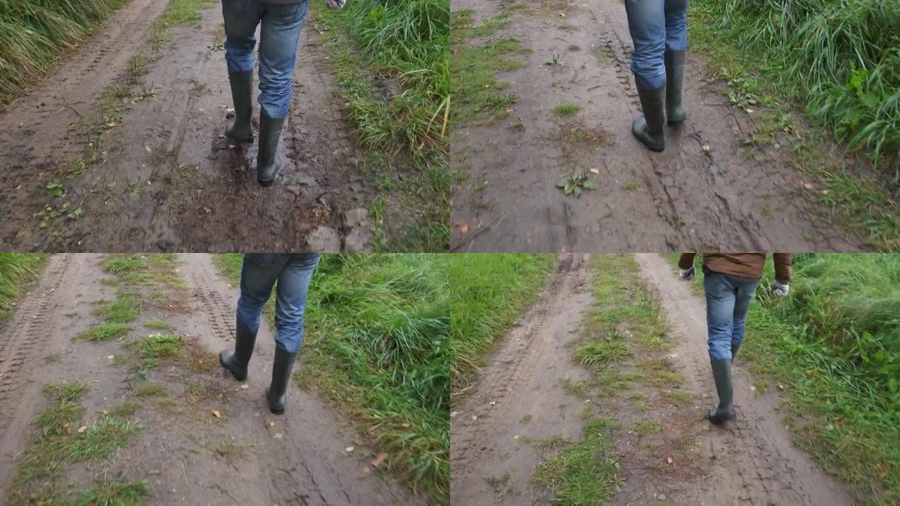 农民穿着牛仔裤和橡胶靴走在泥泞的道路上。