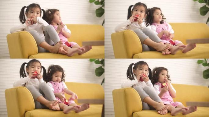 吃苹果的孩子两个小孩坐在沙发上