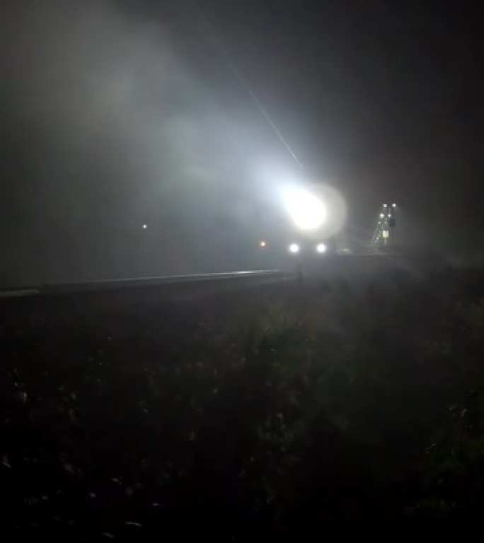 火车探照灯穿过夜雾。火车提供标志-垂直镜头
