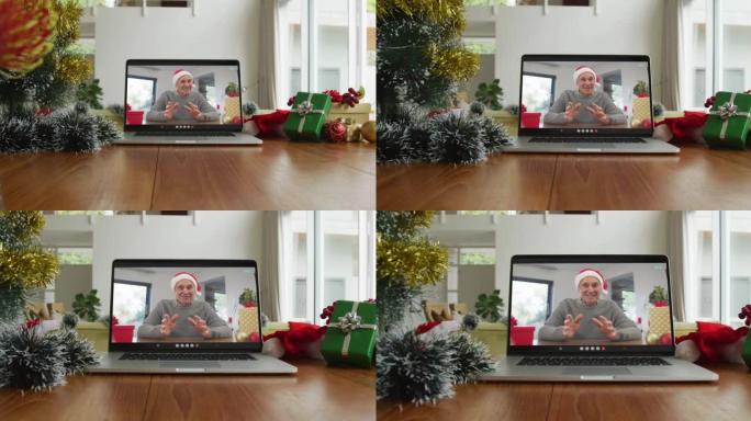 微笑的白人男子戴着圣诞老人的帽子在笔记本电脑上的圣诞节视频通话中