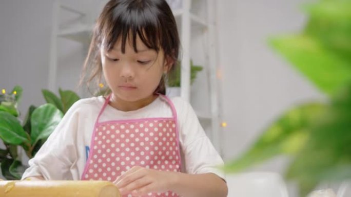 亚洲女孩使用饼干切割器成型自制饼干庆祝圣诞节，生活方式概念。