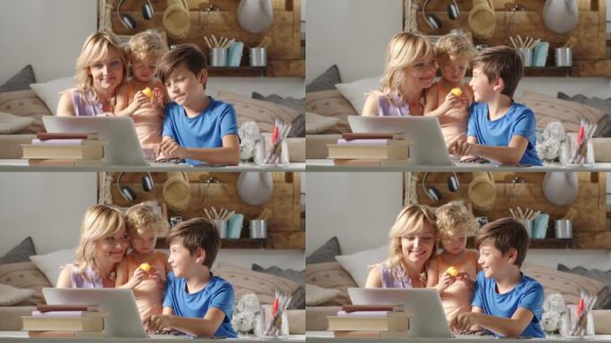 家庭幸福，有儿子和女儿的母亲玩得开心，有孩子的父母在笔记本电脑上浏览互联网，男生在显示器上展示一些东