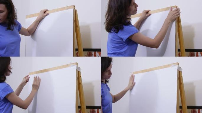 一名妇女用纸带将一大张绘图纸贴在画架上