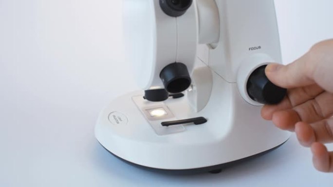 科学家在白色现代显微镜中调整焦点