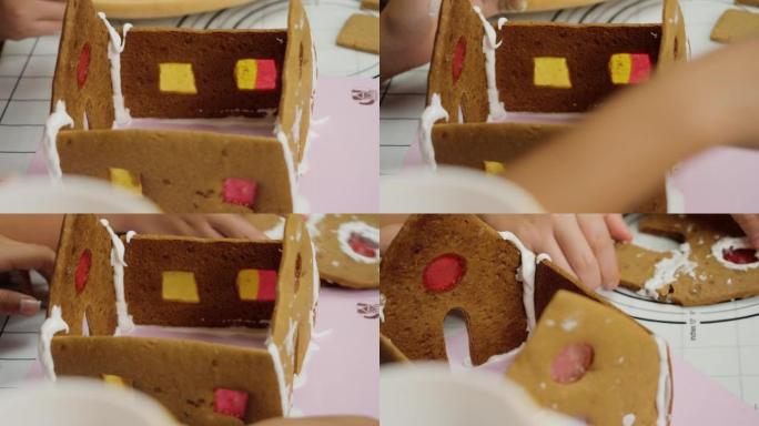 孩子的手在晚上在家与姐姐一起制作姜饼屋，圣诞节庆祝生活方式。
