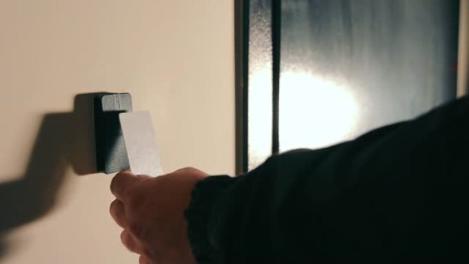 一只男性手拿着卡作为锁的电子钥匙来打开门。电子现代开门方式