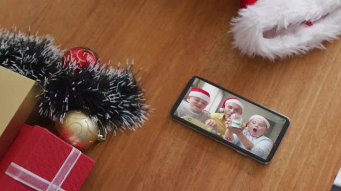 微笑的高加索家庭戴着圣诞老人的帽子，在智能手机上播放圣诞节视频通话
