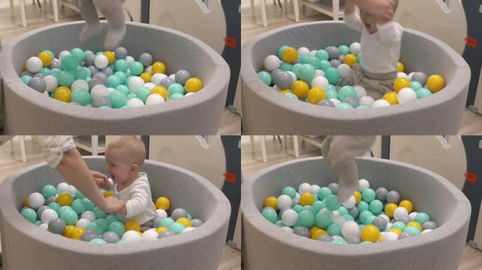 快乐的母亲和她的宝宝在软球坑池玩五颜六色的球，高加索男婴在儿童干池玩得开心，玩得开心。