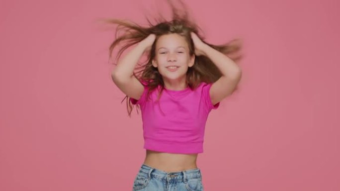 有趣的精力充沛的小女孩孩子皱着长长的金发，摇头，玩得很开心。儿童护发化妆品广告