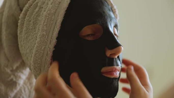一名妇女使用纸黑色面膜护肤的特写镜头