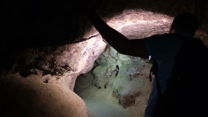 一个人用火炬探索洞穴的剪影。