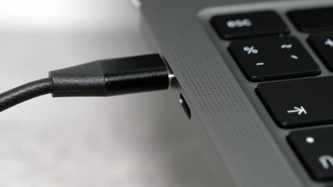 特写女人用手从笔记本电脑上拉出USB C型电缆