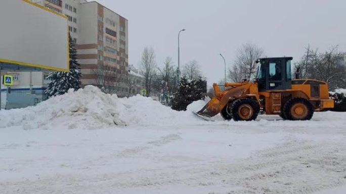 冬天。降雪期间，拖拉机清扫车使用铲斗清除道路上的积雪。市政机械汽车收割清除城市积雪。公用事业工人坐在