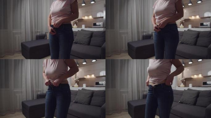 腹部妇女在室内体重增加后拉起紧身牛仔裤