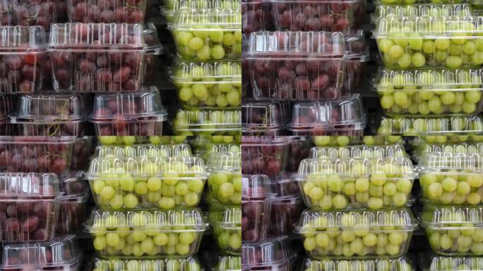 超市中塑料盒中的新鲜红色和绿色葡萄特写。