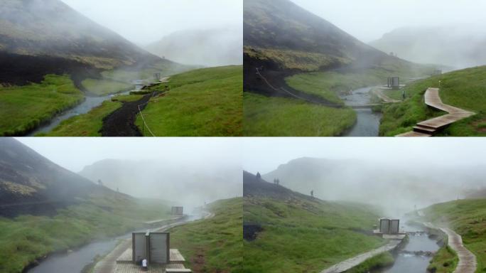 雷克雅达勒河谷的鸟瞰图，温泉河和游泳池，郁郁葱葱的绿草草地和带有地热蒸汽的山丘。在冰岛的温泉中沐浴的