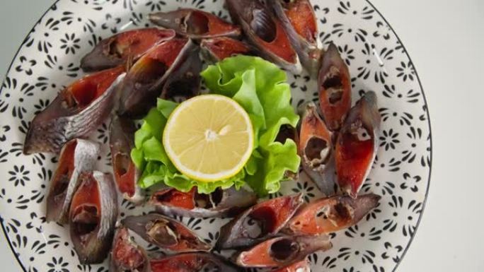 海鲜，咸味多汁的鱼片，鱼子酱，生菜和柠檬放在白色盘子上，特写镜头