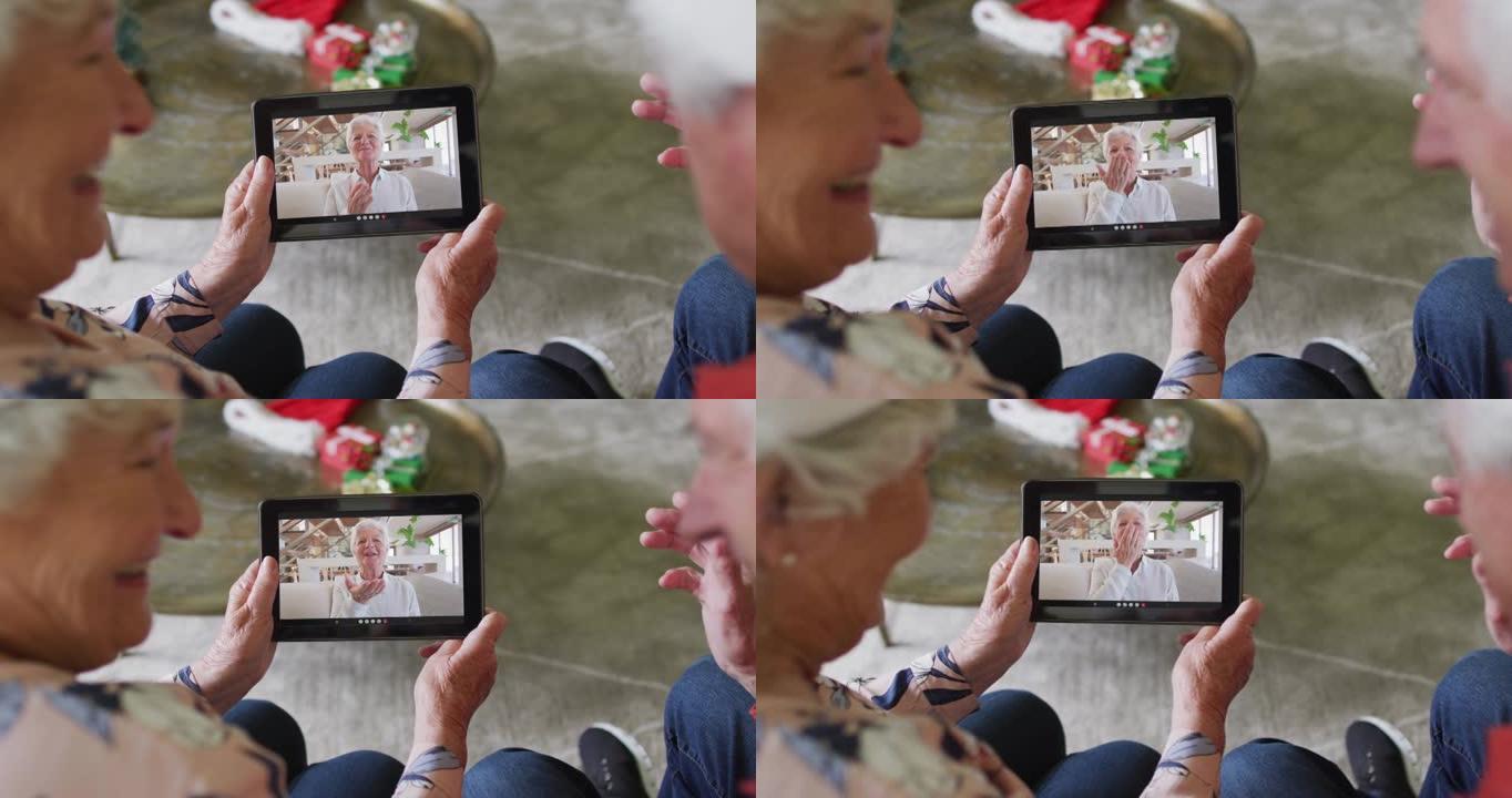 白人高级夫妇微笑着使用平板电脑与屏幕上的女人进行圣诞节视频通话